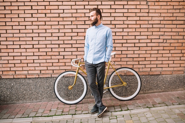 Hombre con bicicleta cerca de la pared de ladrillo