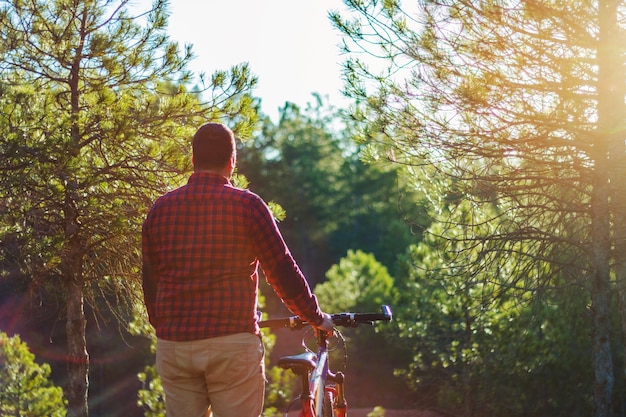 Hombre con bicicleta mirando a bosque