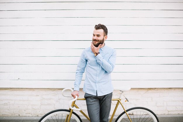 Hombre con bicicleta tocando la barba