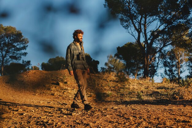 Hombre con binoculares caminando en la naturaleza