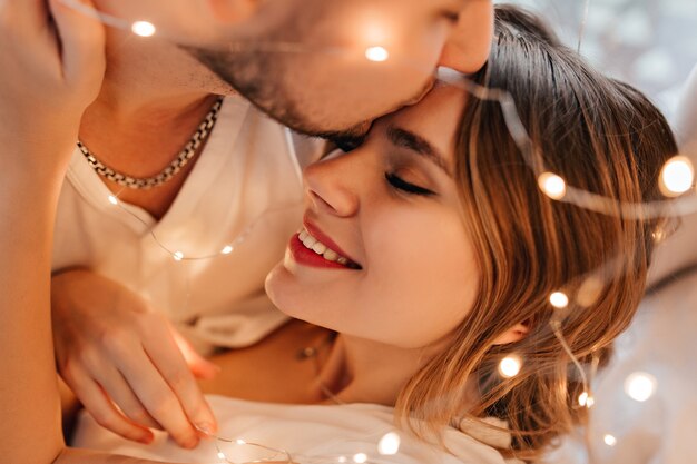 Hombre blanco besando a la novia en la frente. Retrato de primer plano de esposo amoroso expresando ternura a la esposa.