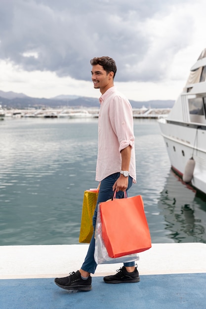 Hombre con bolsas de compras cerca del puerto