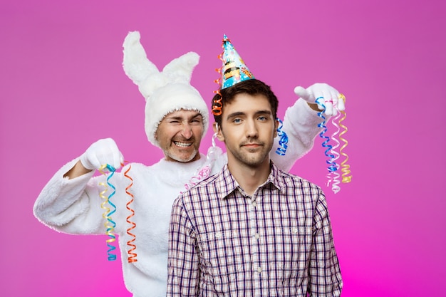 Foto gratuita hombre borracho y conejo en la fiesta de cumpleaños sobre la pared púrpura.