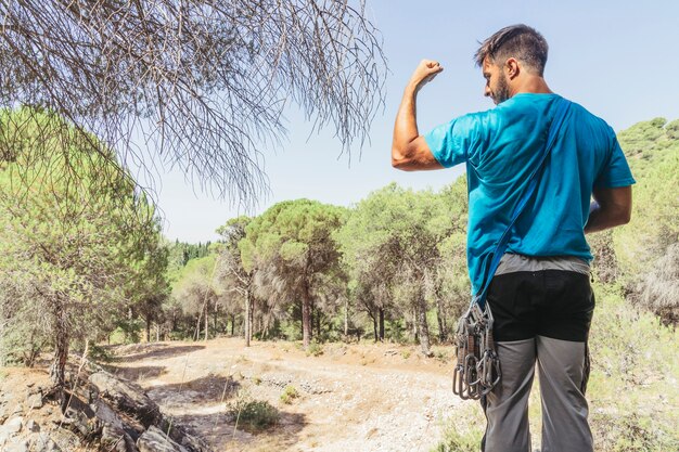 Hombre en bosque mostrando músculos