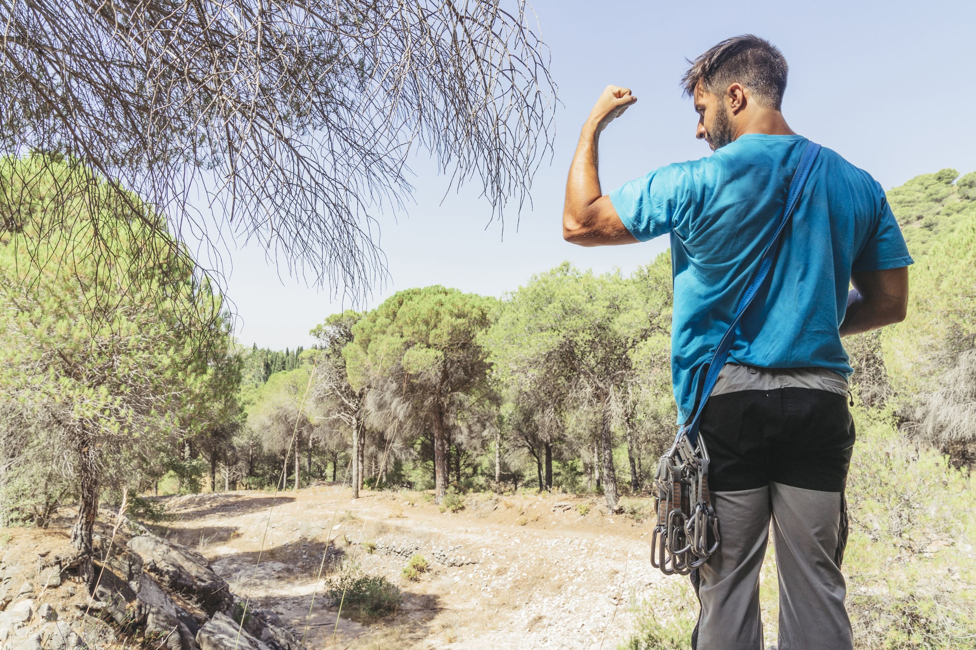 Hombre en bosque mostrando músculos