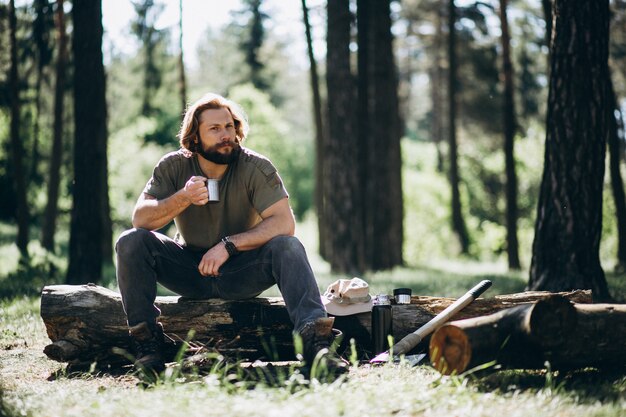 Hombre en el bosque con té por fuego