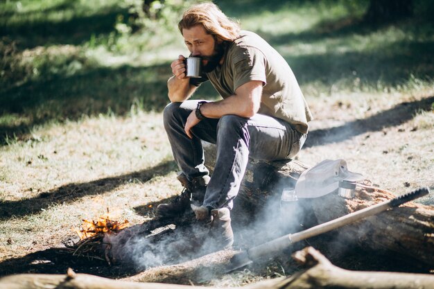 Hombre en el bosque con té por fuego