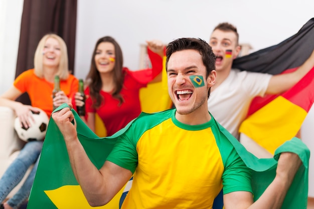 Hombre brasileño emocionado con sus amigos animando partido de fútbol