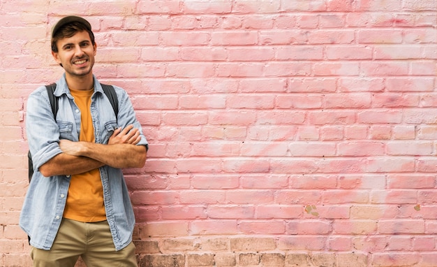 Foto gratuita hombre con brazos cruzados con fondo rosa