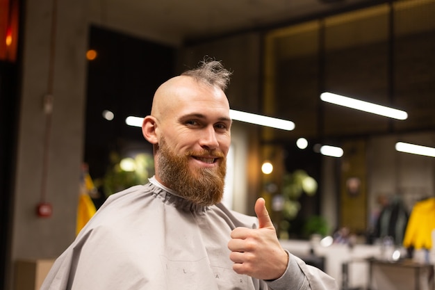 Hombre brutal europeo con barba cortada en una barbería