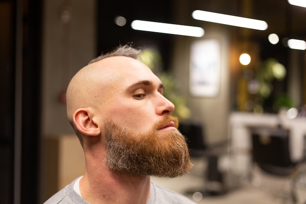 Hombre brutal europeo con barba cortada en una barbería