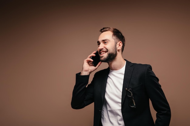 Hombre de buen humor hablando por teléfono con fondo marrón