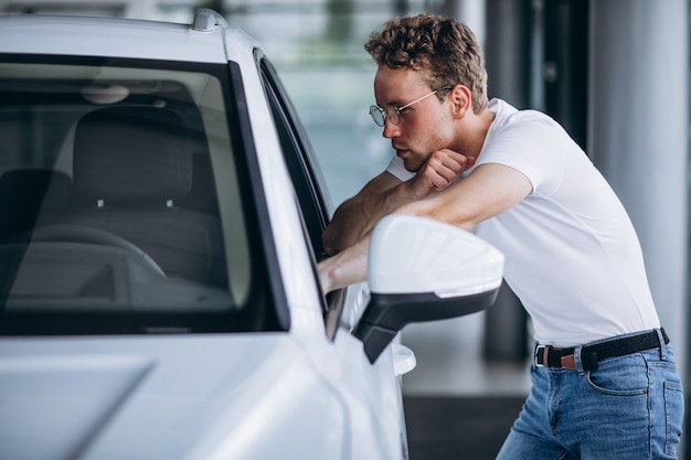 Hombre buscando un coche en una sala de exposición de coches.