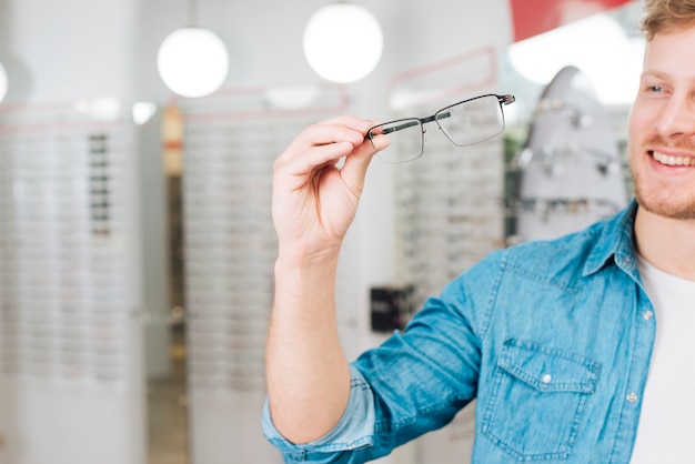 Hombre buscando gafas nuevas en óptico