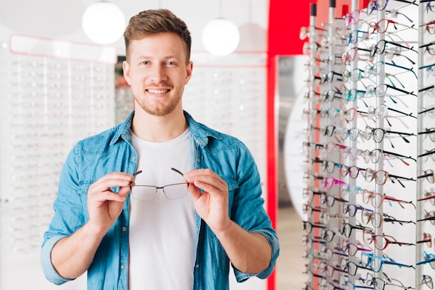 Hombre buscando gafas nuevas en óptico