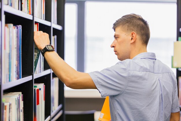 Hombre buscando libro en la biblioteca