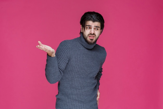 El hombre con cabello largo y barba abre las manos y parece confundido o inexperto.