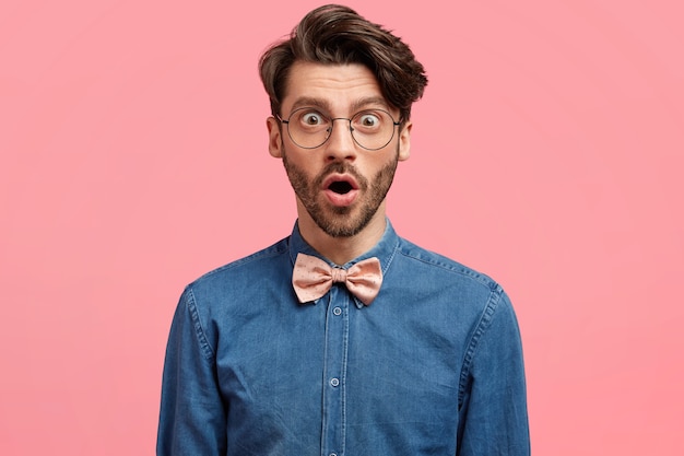 Foto gratuita hombre de cabello oscuro vestido con pajarita rosa y camisa vaquera