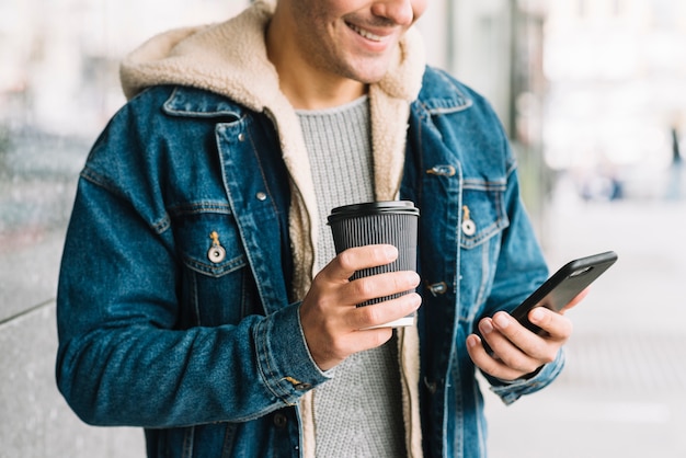 Foto gratuita hombre con café y smartphone en entorno urbano