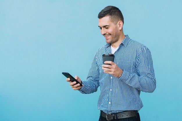 Hombre con café y smartphone en entorno urbano