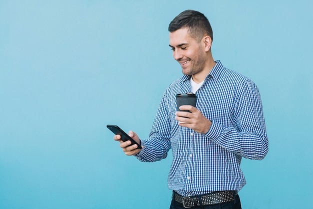 Hombre con café y smartphone en entorno urbano