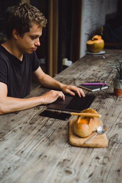 hombre en una cafetería trabajando con una computadora portátil, comer, trabajar, teléfono inteligente