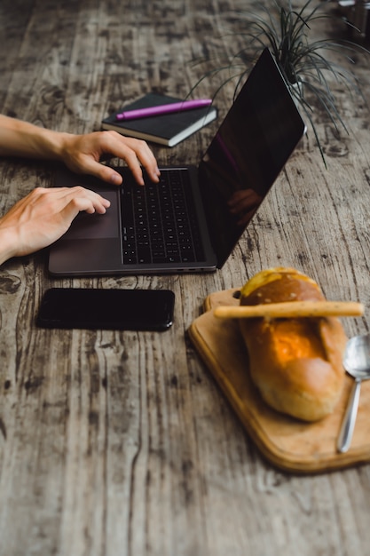 hombre en una cafetería trabajando con una computadora portátil, comer, trabajar, teléfono inteligente