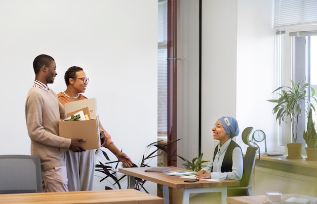 Hombre con caja de pertenencias que se presenta a compañeros de trabajo en su nuevo trabajo