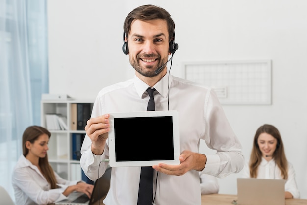 Hombre en call center enseñando tableta