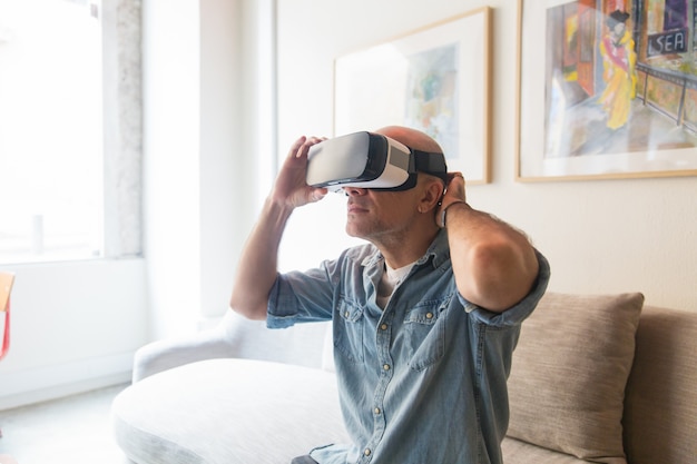 Hombre calvo disfrutando de la experiencia de realidad virtual en casa