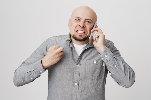 Foto gratuita hombre calvo enojado cabreado aprieta el puño, discutiendo por teléfono