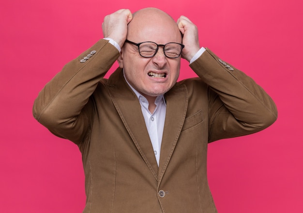 Hombre Calvo de mediana edad en traje con gafas volviendo loco apretando los puños gritando