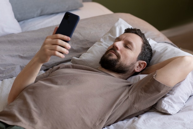 Hombre en la cama con teléfono inteligente