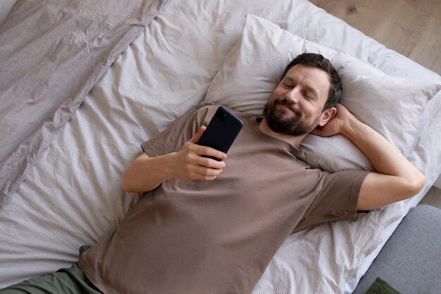 Hombre en la cama con teléfono inteligente
