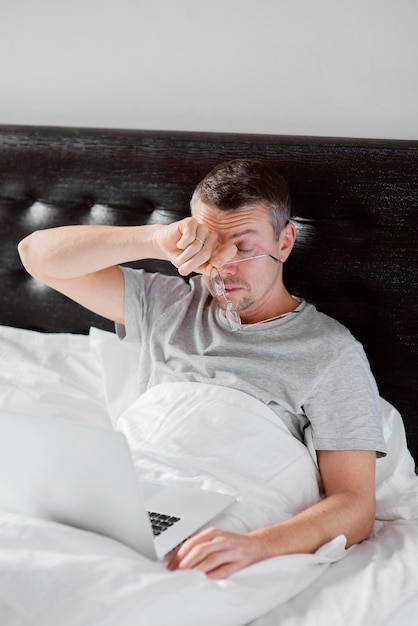 Hombre, en cama, usar la computadora portátil