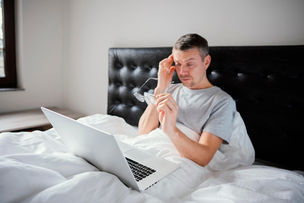 Hombre, en cama, usar la computadora portátil