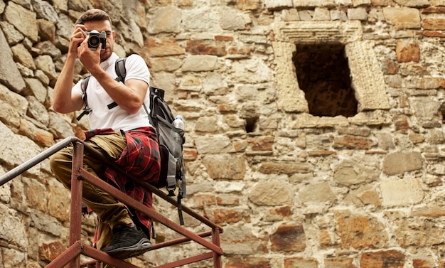 Foto gratuita hombre con cámara en las escaleras del castillo tomando fotos