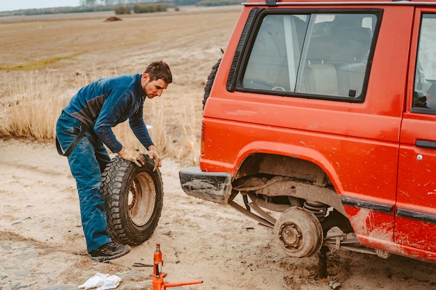 Foto gratuita el hombre cambia la rueda manualmente en un camión todoterreno 4x4