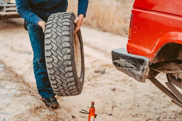 El hombre cambia la rueda manualmente en un camión todoterreno 4x4