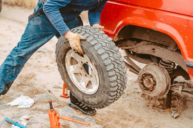 El hombre cambia la rueda manualmente en un camión todoterreno 4x4