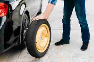 Foto gratuita hombre cambiando el neumático del coche con rueda de repuesto