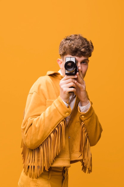 Foto gratuita hombre con un camcorder en un escenario amarillo