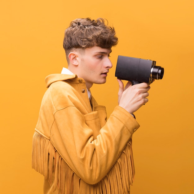 Foto gratuita hombre con un camcorder en un escenario amarillo