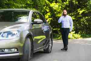 Foto gratuita hombre caminando cerca de coche hablando por teléfono móvil