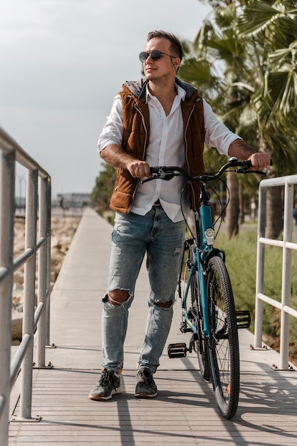 Foto gratuita hombre caminando junto a su bicicleta