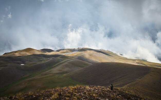 Hombre caminando sobre una montaña con un cielo nublado