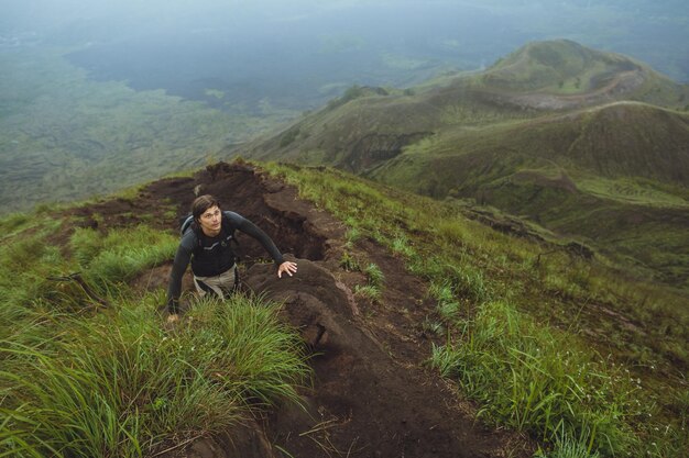 Hombre caminante escalando una pared empinada en la montaña