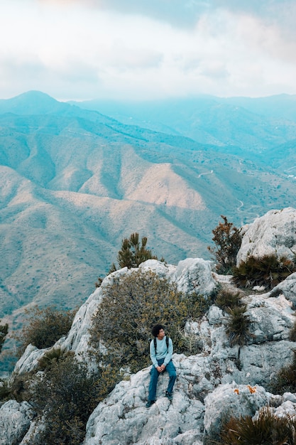 Hombre caminante solo sentado en el paisaje de montaña rocosa