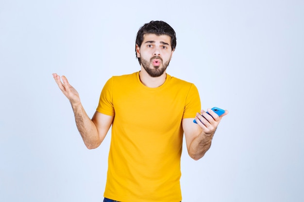 Hombre de camisa amarilla apuntando con su teléfono inteligente y disfrutándolo.