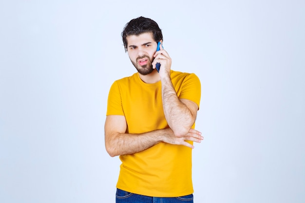 Hombre de camisa amarilla hablando por teléfono.